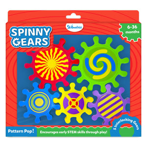 Skillmatics Spinny Gears Pattern Pop toy box on a red background for ages 6–36 months. Five interlocking plastic gears shown: red sunburst, green blue-yellow spiral, blue concentric circles, yellow with purple cross, and purple with yellow stripes. Labels read "5 Interlocking Gears," "Pattern Pop!" and "Encourages early STEM skills through play!"
