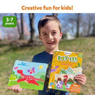 Smiling boy holding Dot It! Dinosaur-themed sticker activity book and completed sticker art