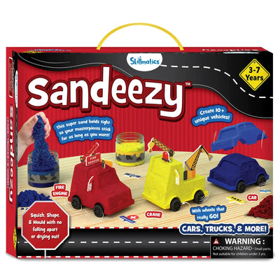 The Sandeezy box front shows jars of blue, yellow, and red kinetic sand, moulded vehicles including a red fire engine, a yellow crane truck, and a blue car base. Callouts highlight features like “Create 10+ unique vehicles,” “Sand holds tight,” and “Squish, Shape & Mould.” A “3–7 Years” badge is placed on top. The Skillmatics logo, warning label, road graphic, and included accessories like signs and wheels appear across the packaging.