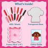 Flat lay 'What's Inside' panel for Skillmatics Stixels kit showing 400+ colorful cylindrical stixels in shades of red, brown, white and black, a transparent perforated base board shaped like a character silhouette, a pink wavy frame, and a color guide card featuring a sample puppy design.