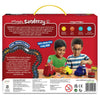 The back of the Sandeezy box features a red background with a description panel explaining the super sand’s texture and benefits, alongside icons for creative thinking, fine motor skills, process planning, and social communication. Two children build a red fire engine, yellow taxi, and blue ice-cream van using sand and accessories. A curved road graphic, sand tubs, manufacturing details, safety icons, and the Skillmatics website are shown at the bottom.