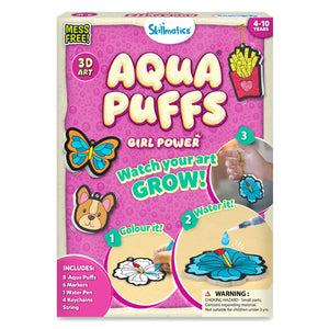 Front view of Skillmatics Aqua Puffs Girl Power 3D Art kit box with bright pink bubble background. Text reads “Mess Free,” “4–10 Years,” and “Watch your art grow.” Includes images of butterfly, dog face, fries, and flower designs. Step visuals show color, add water, and attach keychain. Box lists 8 Aqua Puffs, 6 markers, 1 water pen, 4 keychains, and string.