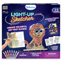 Skillmatics Light-Up Sketcher kit for ages 4–8, featuring a glowing animal-shaped lion display board, 12 tracing guides, reusable sticker sheet, eight markers, LED light strip, two stands, dust cloth and instruction manual. Dark blue packaging promotes colorful, reusable glowing artwork.