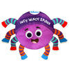 A front-facing view of the Skillmatics Incy Wincy Spider plush toy on a white background. The spider has a round purple body with a smiling embroidered face, large stitched eyes, and the words “Incy Wincy Spider” stitched across the top. Eight soft, striped legs in bright colors extend outward, showing varied fabric textures designed for gripping, squeezing, and sensory exploration by babies and toddlers.