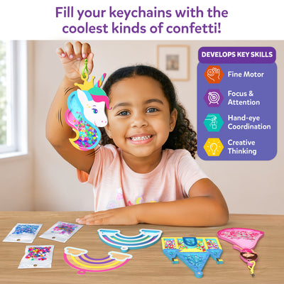 A smiling child sits at a table holding a unicorn shake-it keychain filled with multicolored confetti. On the table are rainbow and castle foam shake-its, confetti packs, and keychain parts. A side panel titled “Develops Key Skills” lists icons for fine motor skills, focus and attention, hand-eye coordination, and creative thinking, with text stating it is suitable for ages 4–9.