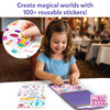 Smiling girl in blue shirt placing stickers into a purple Peelies spiral-bound activity book at a white table. A sticker sheet with princess-themed accessories lies beside the book. Circular inset shows a close-up of a hand peeling a butterfly cat sticker from a sheet with crowns, shoes, and accessories. Text reads Create magical worlds with 100 plus reusable stickers and Peel, Place, Reuse. Mess Free badge shown.