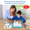 A smiling woman in a blue shirt and a boy in a blue top sit at a wooden table using the Skillmatics Toy Story My Story Art Kit. The boy places character stickers onto a blue story pad while the woman holds a vocabulary card. Markers, sticker sheets, and written story pages are spread on the table. Age label reads 