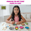 Smiling young girl seated at a table coloring a butterfly Aqua Puff cutout with a marker. Finished designs including Girl Boss text, fries, flower, pear, rainbow, and dog face are placed on the table with gold keychain attachments. Text above reads “Magical 3D Art That Pops to Life!” and “Mess Free,” highlighting creative, hands-on craft activity.