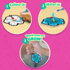 Three circular step visuals on pink background showing how Aqua Puffs work. Step 1 shows a child coloring a white flower cutout with marker. Step 2 shows water pen adding drops to colored design. Step 3 shows finished puffed flower attached to a gold keychain. Text reads “Colour it,” “Water it,” and “Watch your art grow.”