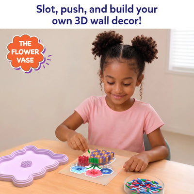 Young child seated at a table assembling the Skillmatics Stixels Flower Vase craft by inserting colorful Stixels into a transparent flower-shaped base placed over a color guide. A lavender frame sits nearby, with extra Stixels organized in a bowl beside the partially completed 3D design.