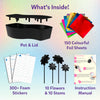 Skillmatics Foil Fun Mosaics kit contents display showing black flower pot and lid, colourful foil sheets, foam sticker sheets, flower shapes with stems, and instruction manual. Text highlights included items: pot and lid, 150 colourful foil sheets, 300+ foam stickers, 10 flowers, 10 stems, and instructions.