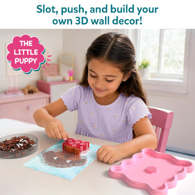 Young girl sitting at a table engaging with Skillmatics Stixels 3D art kit, carefully inserting colored stixel pegs into a transparent base using a color guide. The scene shows a pastel pink creative workspace with finished puppy design forming, bowls of stixels, and a calm, focused play activity.