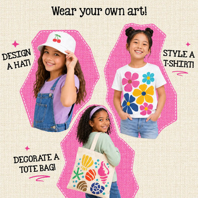 Three children showcasing Skillmatics Iron-Its wearable art. Left: girl wearing white bucket hat with cherry iron-on design. Right: girl in white tee featuring large colorful flower print. Center-bottom: girl carrying canvas tote bag decorated with colorful seashell and ocean designs.