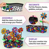 Skillmatics Foil Fun Mosaics activity guide showing the creative process: decorating flowers, leaves, pebbles, and pot with foil sheets; assembling stems into the pot; and displaying the finished colourful 3D mosaic flower decoration. Images show hands applying foil pieces and the completed sparkling flower pot.