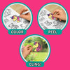 Step-by-step instructional graphic on a pink background showing three circular panels. The first shows a child coloring a unicorn sticker with a paint marker, the second shows peeling the finished sticker from the sheet, and the third shows holding the completed unicorn sticker against a glossy surface. Curved arrows connect the steps labeled Color, Peel, and Cling.