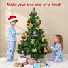 Children wearing festive pyjamas decorate a Christmas tree with colourful Skillmatics Foil Fun ornaments. The tree features handmade foil stars, stockings, bells, gifts and baubles, showcasing a creative holiday craft activity where children personalise decorations for display.