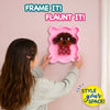Young girl seen from behind carefully holds a pink wavy frame mounted on a wall, showcasing a completed 3D puppy design made with Stixels pegs. Bold text reads ‘FRAME IT! FLAUNT IT!’ and ‘STYLE YOUR SPACE!’, highlighting DIY wall décor in a soft pastel interior setting.