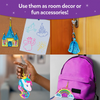 A collage shows finished shake-it keychains used in everyday settings. A castle shake-it hangs on a corkboard near children’s drawings, a princess shake-it hangs from a door handle, a unicorn shake-it is held in a child’s hand, and a rainbow shake-it is clipped to a pink backpack. Text above reads “Use them as room decor or fun accessories!”