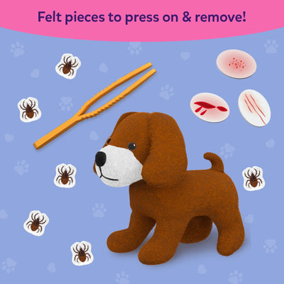 Skillmatics Vet Set showing a brown plush puppy surrounded by removable felt tick pieces, orange tweezers, and reusable injury patches representing bruises, cuts, scratches, and rashes. Children can attach and remove the felt pieces during imaginative pretend veterinary play.