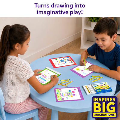 Two children sit at a round blue table using the Skillmatics Picture Sprouts activity book and retractable crayons to complete colorful drawings. Finished artwork, loose crayons, and the crayon box are spread across the table, showing a shared creative activity in a bright indoor play space.