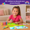 Young girl happily creating colorful sand art with pens and stickers from Sand-Tastic Art
