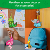 A collage shows animal-shaped confetti keychains used in different settings. A crocodile keychain hangs on a corkboard beside children’s drawings, an elephant hangs from a door handle, a pink flamingo keychain is held in a child’s hand, and a giraffe keychain is clipped to a blue backpack. Text above reads “Use them as room decor or fun accessories!”