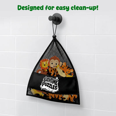 Black mesh storage bag labeled “Bathtime Puzzles” hangs from a bathroom wall hook against white tiles. Inside the bag are colorful foam animal puzzle pieces, including a lion, monkey, and tiger. Green text at the top reads “Designed for easy clean-up!” highlighting convenient storage after bath play.