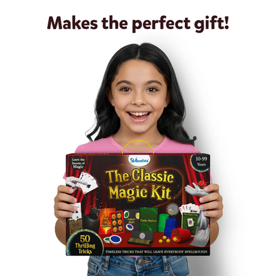A young girl in a pink t-shirt excitedly holds the Skillmatics Classic Magic Kit, with the box prominently featuring the kit's name and colorful magic props like cards, cups, and trick tools. The girl smiles broadly, radiating excitement, with a caption above reading, 'Makes the perfect gift!' The image conveys joy and fun, highlighting how the magic kit can bring endless entertainment for kids aged 10-99 years.