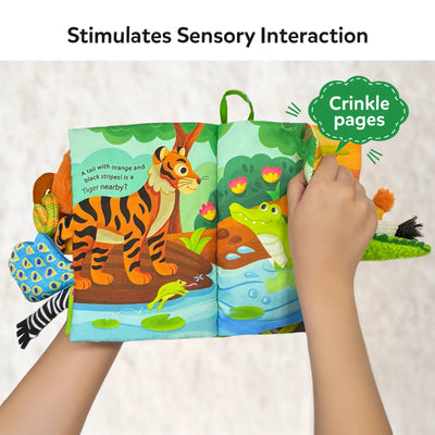 A hand interacting with the 'Whose Tail is That?' sensory cloth book, turning the pages that feature a tiger with a striped tail and a crocodile. The page has crinkly fabric sections, enhancing sensory interaction for the child. The plush tails of various animals, like a monkey and zebra, are attached to the book for tactile engagement, promoting early learning and sensory development.
