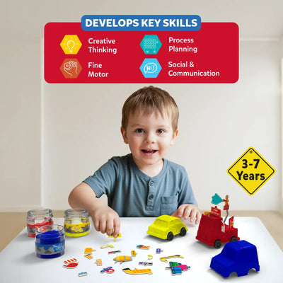 A young boy sits at a table surrounded by jars of blue, yellow, and red kinetic sand while attaching accessories to moulded sand vehicles—a yellow taxi, a red fire engine, and an unmolded blue car. Various signs and props are scattered around him. Above him, a skills panel features icons for creative thinking, process planning, fine motor skills, and social communication. A yellow road-sign badge reads “3–7 Years.”