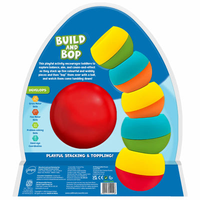 The back of the Build And Bop toy packaging displays the logo at the top, a description of how toddlers stack colourful wobbly pieces and knock them down with a ball, and a large red soft ball centered in the layout. On the left, icons list skill benefits such as 'gross motor', 'fine motor', 'problem-solving', and 'hand-eye coordination'. On the right, five wobbly pieces are stacked, and manufacturing and safety information appears along the bottom.
