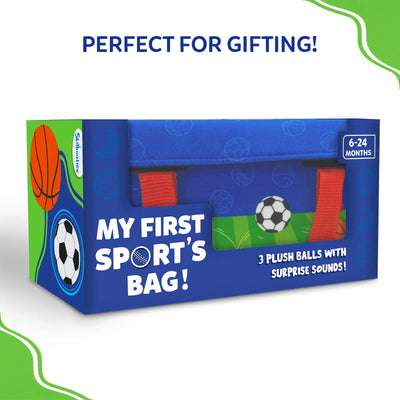 Rectangular retail box displaying “My First Sport’s Bag!” in bold white text on a blue background with sports illustrations. A clear window reveals the blue fabric bag and red handles inside. Text on the front reads “3 plush balls with surprise sounds,” with an age badge of 6–24 months. The design emphasizes premium gifting-ready packaging.
