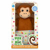 A boxed interactive monkey plush toy is shown inside cream-colored packaging decorated with multicolored dots. The large brown monkey is visible through a clear window, holding a polka-dotted cloth. Labels on the box highlight “Battery Operated” and “12+ Months.” A tail-shaped graphic says “Press my tail to play peek-a-boo!” and the bottom panel reads “Interactive plush toy with audio and motion.”