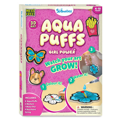 Angled front view of Skillmatics Aqua Puffs Girl Power 3D Art kit box on pink bubble background. Large “Aqua Puffs” title with butterfly, dog face and fries illustrations. Step visuals show color, add water and attach keychain. Includes list of 8 Aqua Puffs, 6 markers, 1 water pen, 4 keychains and string, with 4–10 years age badge and safety warning.