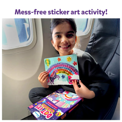 Young girl on airplane holding completed unicorn and rainbow sticker art from Dot it Sparkle Edition