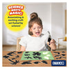 Young girl creating sun paper art with black silhouettes on glowing green mat in nature