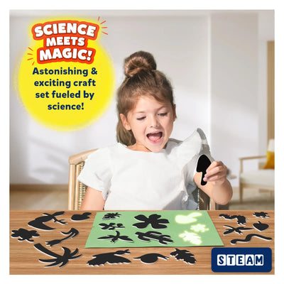 Young girl creating sun paper art with black silhouettes on glowing green mat in nature