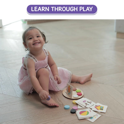Smiling toddler in pink dress playing with Wooden Learning Game on the floor